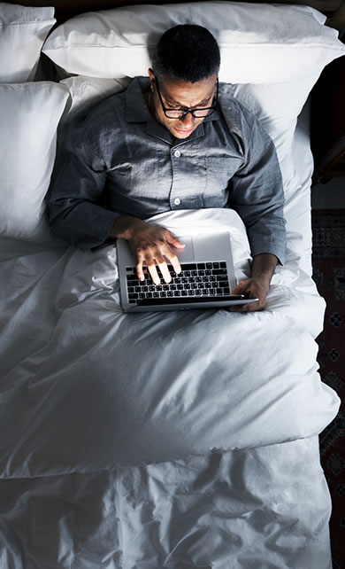 Homem na cama trabalhando com notebook