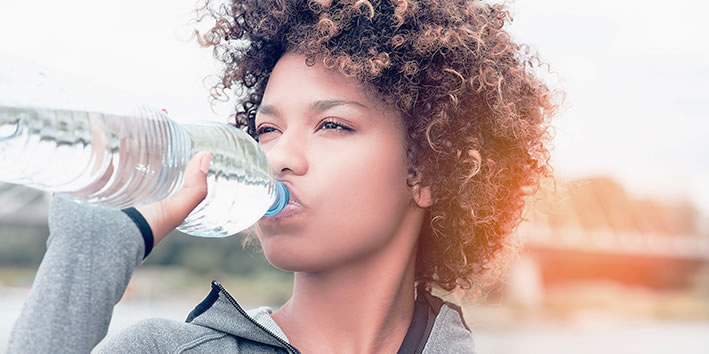 Mulher bebendo agua para prevenir calculo renal