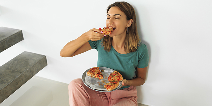 Mulher comendo pizza no chao