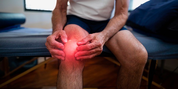 maos no joelho com dor